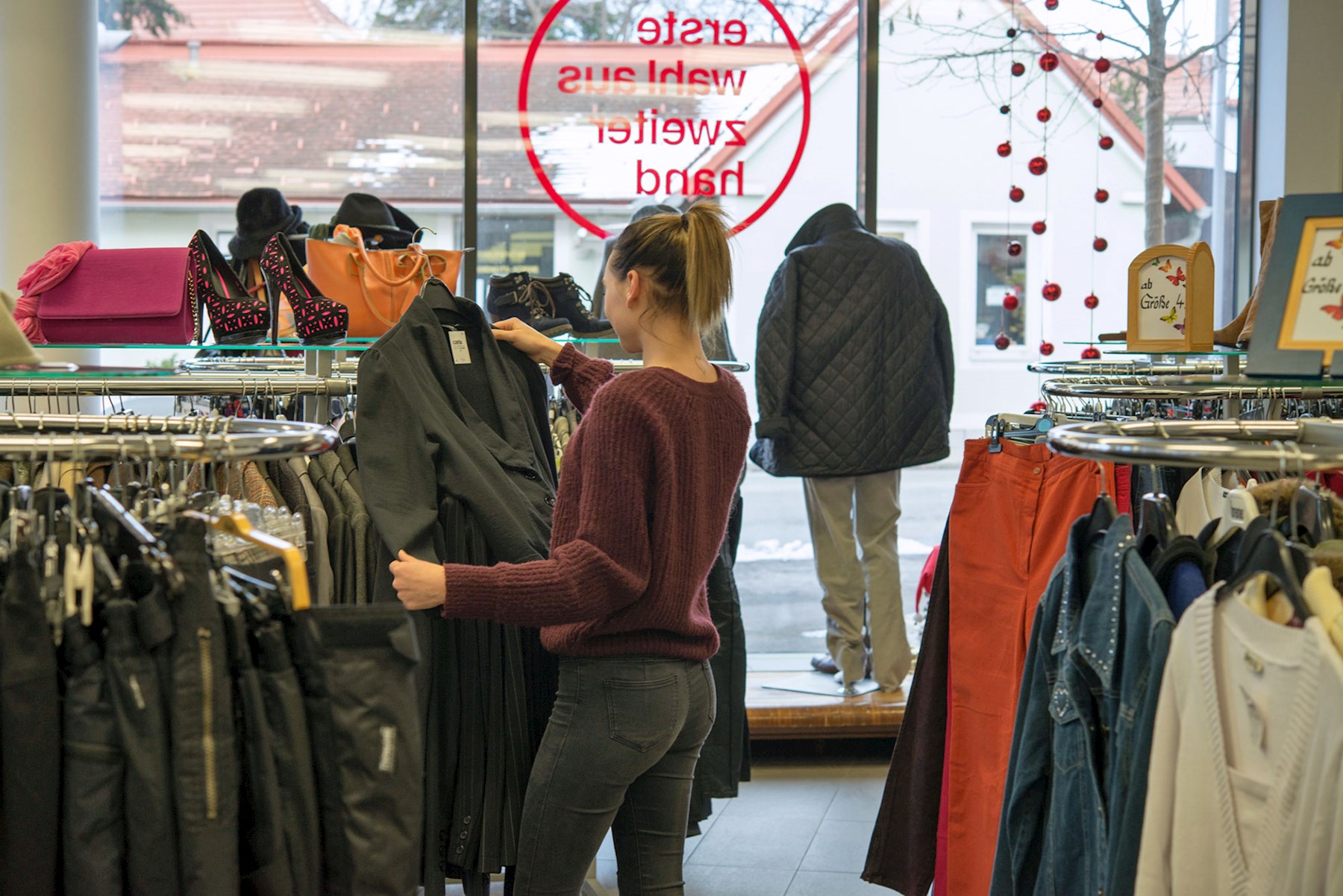 Junge Frau betrachtet einen Mantel in einem Carla-Laden.